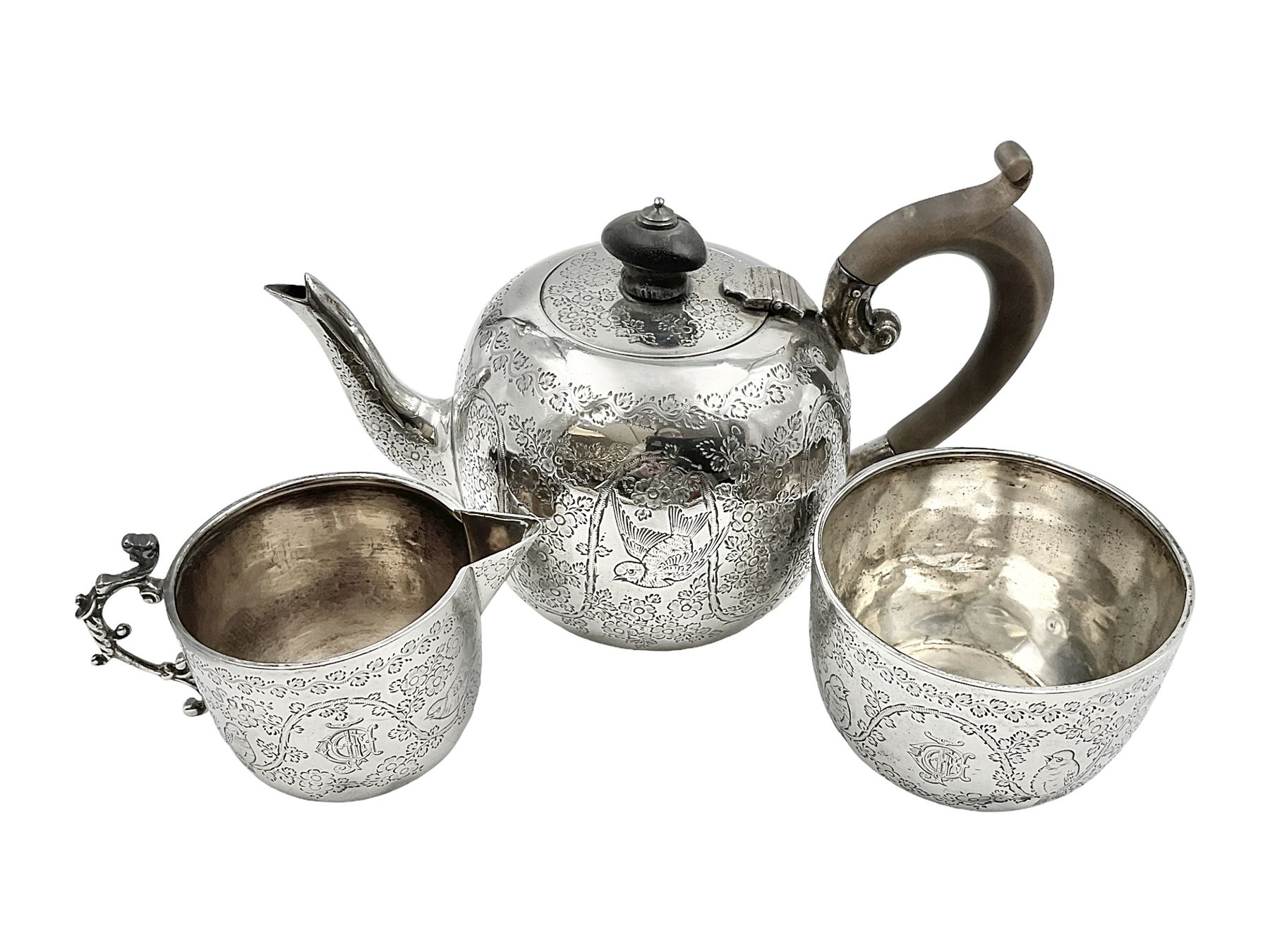 Late Victorian silver bachelors three piece tea service, comprising bullet shaped teapot, open sucrier and milk jug, each engraved with monogram surrounded by birds upon and amidst a blossoming vine, the teapot with scroll capped curved wooden handle and wooden finial to cover, hallmarked Wakely & Wheeler, London 1890, teapot including handle H12cm, sucrier H5.5cm 
