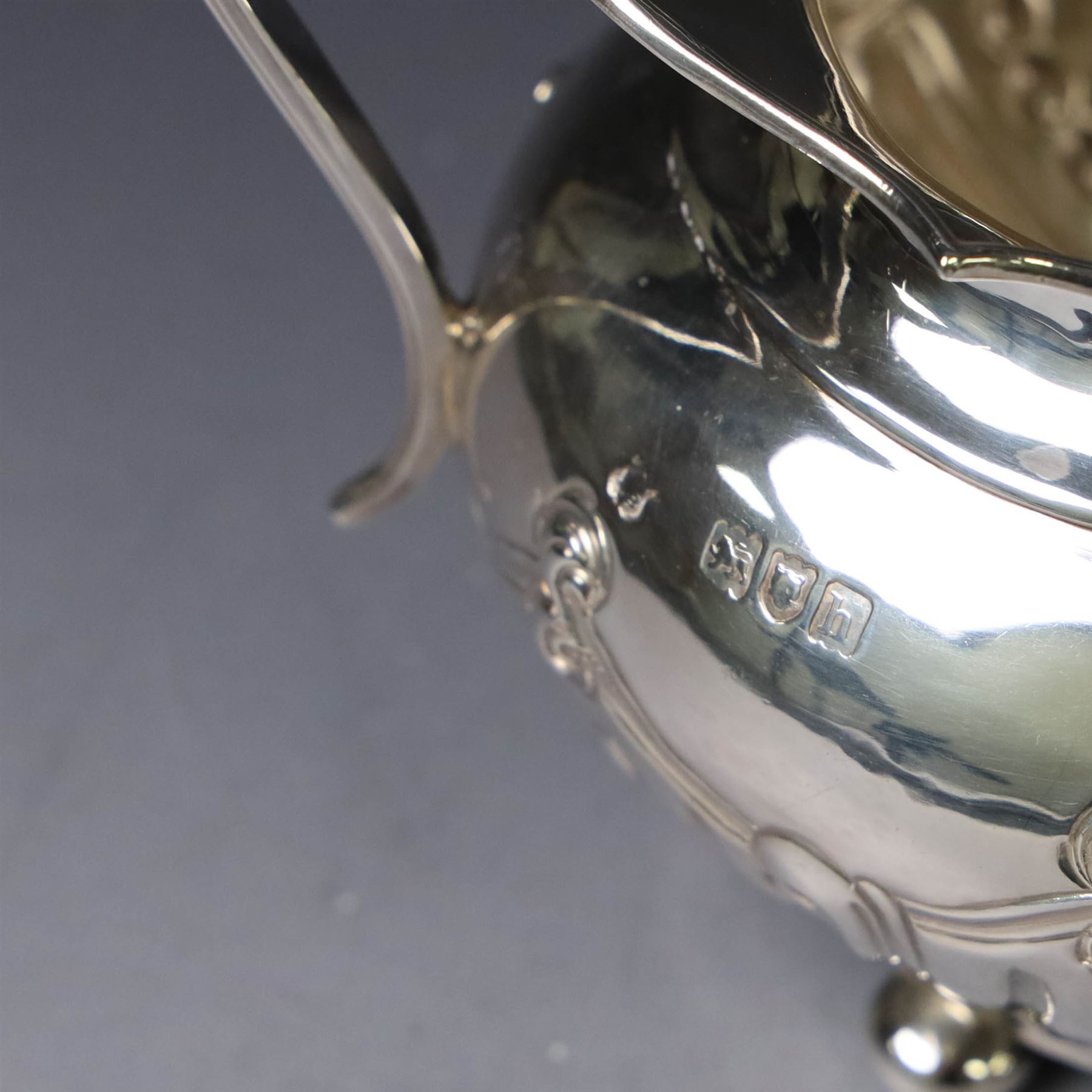 Edwardian silver three piece tea service, comprising teapot, twin handled open sucrier and a cream jug, each of oval form with embossed scrolling decoration and upon four bun feet, the teapot with ebonised wooden handle and finial, hallmarked Thomas Bradbury & Sons Ltd, Sheffield 1903, teapot H16cm