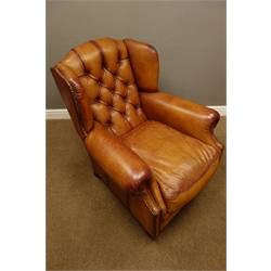  Tetrad Made in England deep club armchair upholstered in tan leather, buttoned back with studded detail, mahogany feet (W85cm, D110cm, H95cm) with matching footstool  