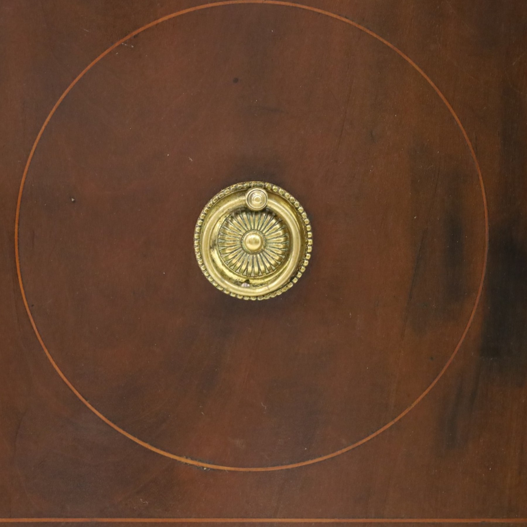 Regency period inlaid mahogany bow-breakfront sideboard, shaped rectangular top with crossbanding and ebony stringing, central convex frieze drawer flanked by cupboard and cellarette drawer, over fan-inlaid spandrels, raised on square tapering supports