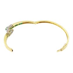 14ct gold emerald and diamond crossover bangle, two oval cut emeralds with round brilliant cut diamond surround, with channel set calibre cut emerald shoulders, stamped 585