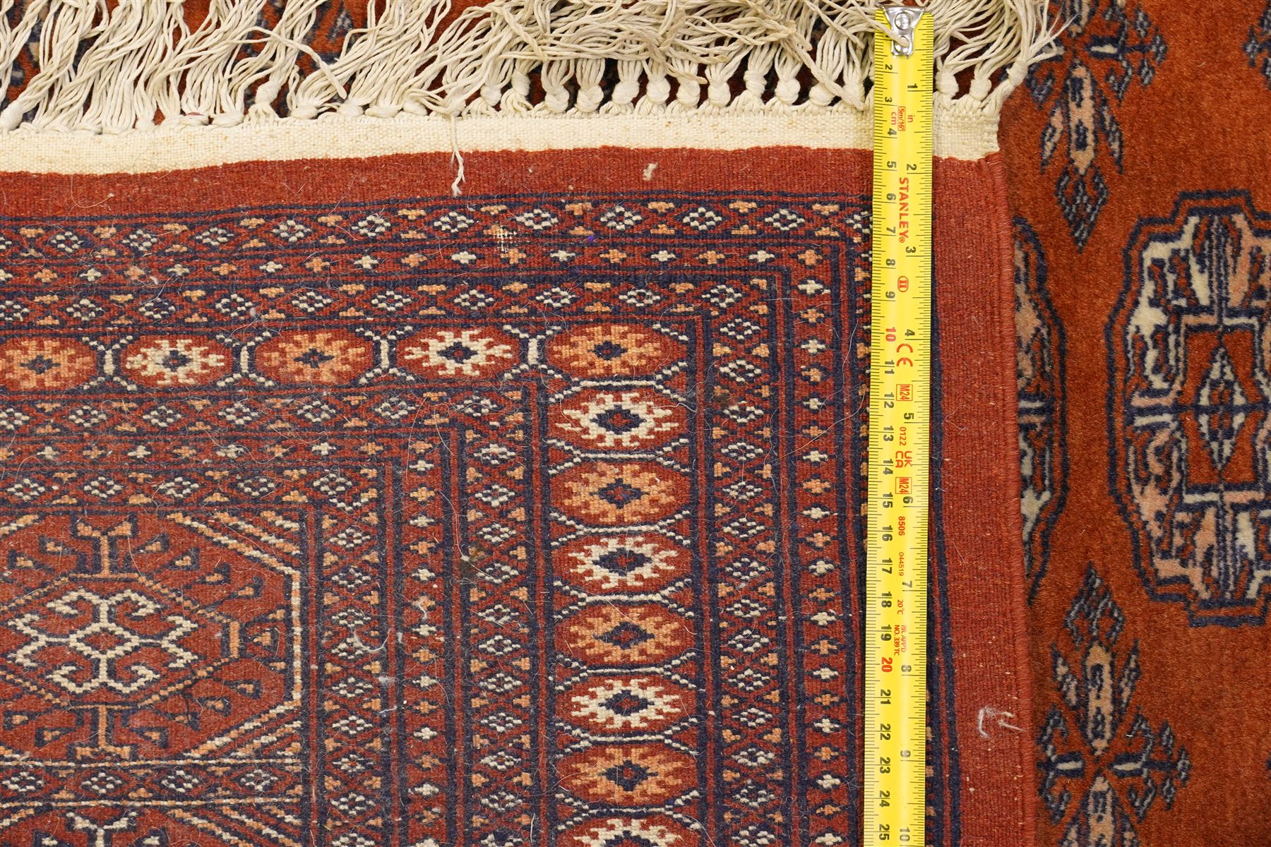 Bokhara hand-knotted carpet, terracotta ground with repeating rows of Tekke guls and geometric motifs, enclosed by multiple geometric borders, with silk highlights, fringed ends