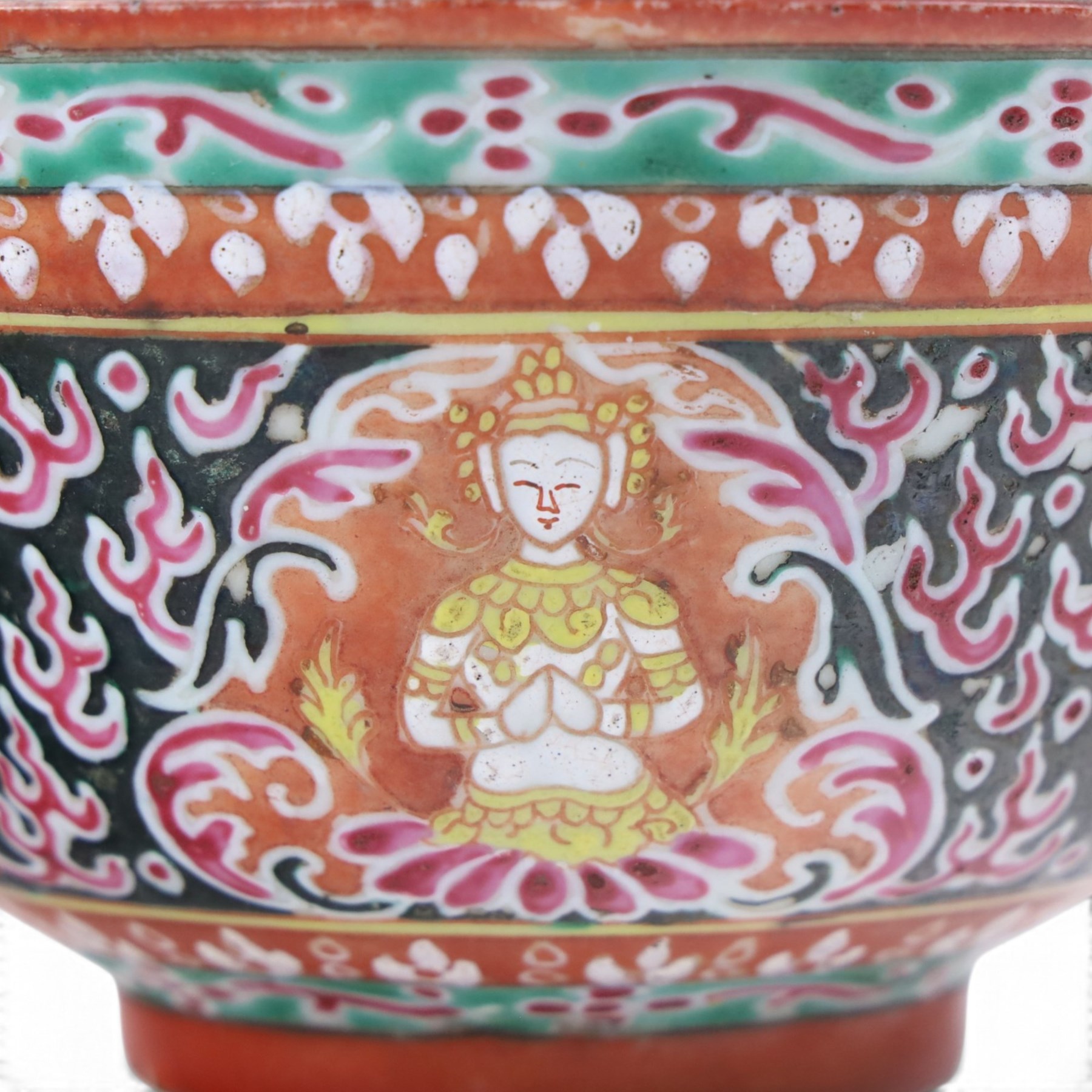Benjarong bowl, the sides painted with alternating images of the Buddhist figures on a black ground embellished with flames, H8cm D15cm
