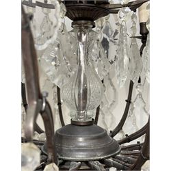Early 20th century continental cut glass and metal chandelier, with sixteen candle style lights on a single tier of scrolled arms, hung with faceted glass drops and centred by a mould-blown and cut glass baluster stem, suspended from a ceiling rose and chain