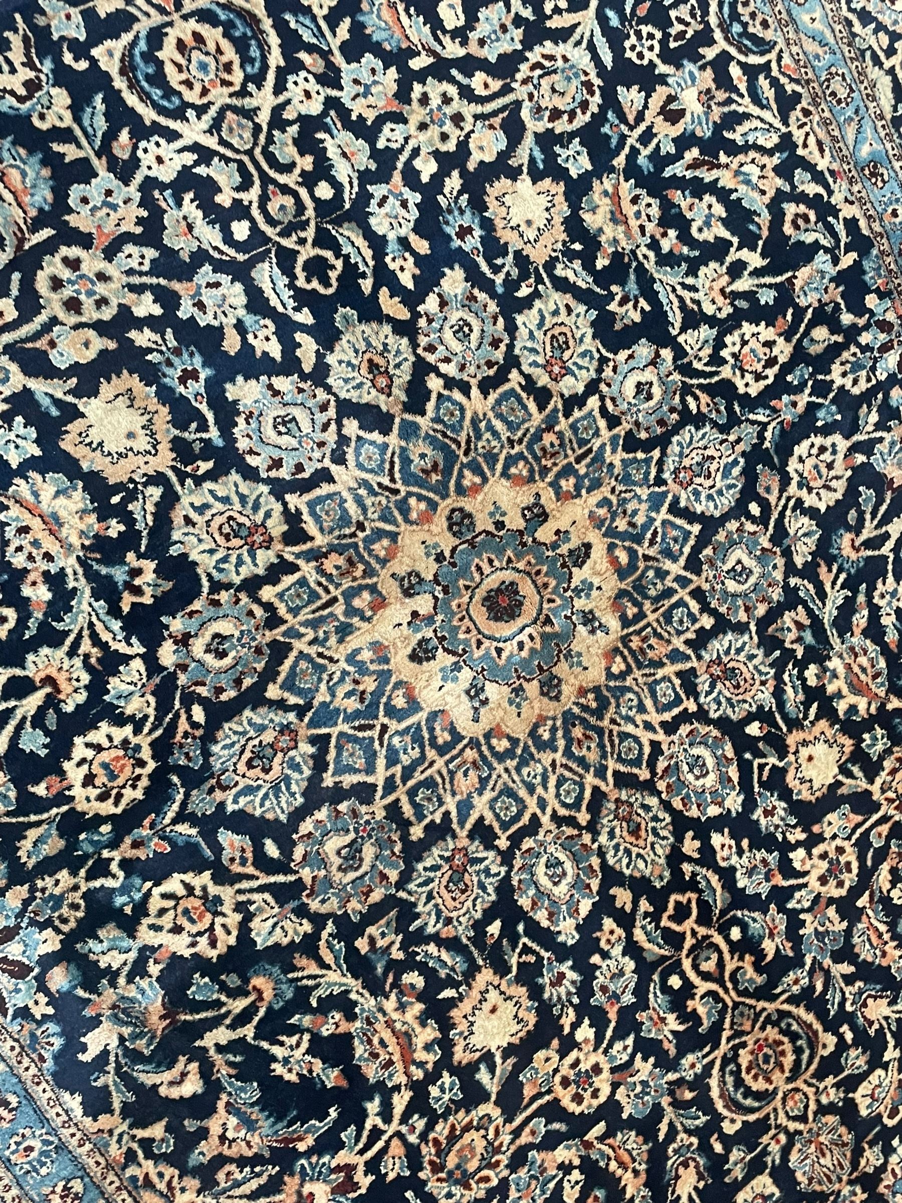 Persian Kashan indigo ground rug, the rosette medallion decorated with projecting palmettes, on a field of swirling leafy branches and decorated with further palmettes, the scrolling border with repeating stylised plant motifs, within floral pattern guard stripes