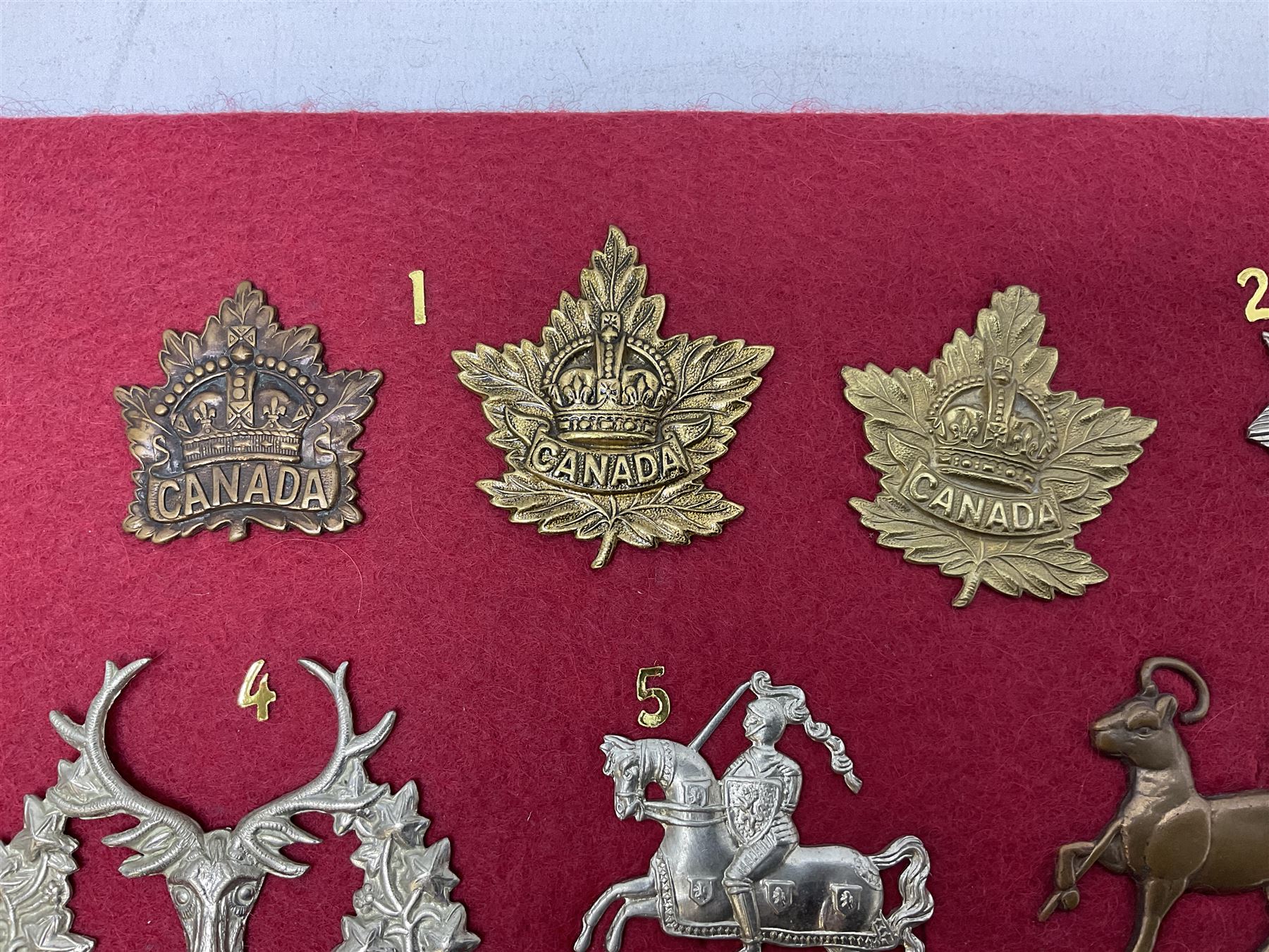 Forty glengarry and cap badges and shoulder titles including Gordon Highlanders, Canada and Canadian Field Artillery, New Zealand Field Artillery and Rifle Regiment, Shropshire Light Infantry, 14th/20th Kings Hussars, 17th Lancers, Northamptonshire Yeomanry, Royal Lincolnshire, Special Air Service, 19th Alexandra P.W.O. Hussars etc; mounted on two boards for display (2)