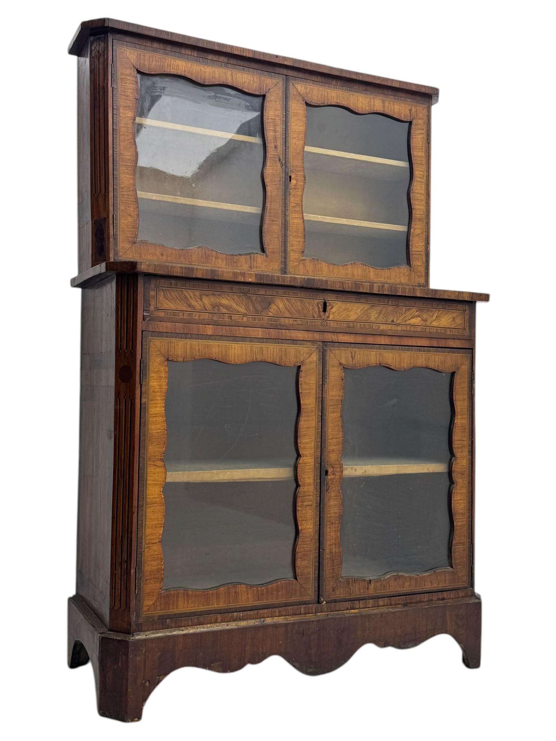 Late 19th century continental display cabinet, the upper section is glazed with twin doors with two upholster shelves, over a lower section with single draw above two glazed cupboard doors on shaped bracket feet