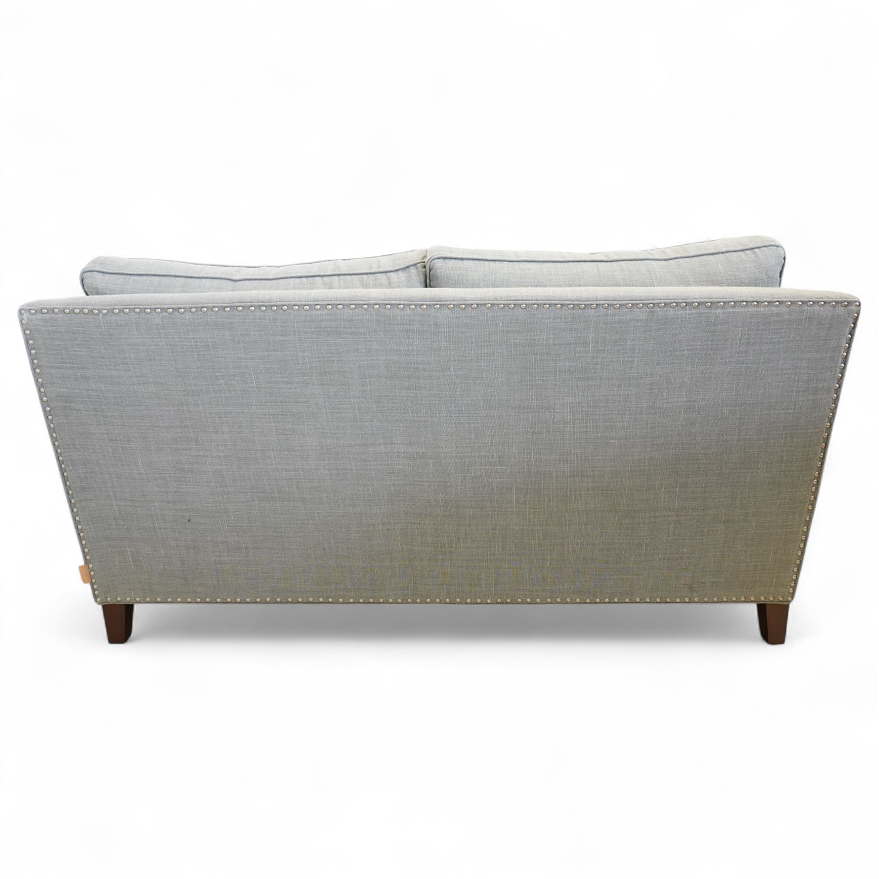 Neptune traditional style two-seat sofa, sloped back rest, gently flared arms, studded upholstered in a light grey fabric on square tapered legs 