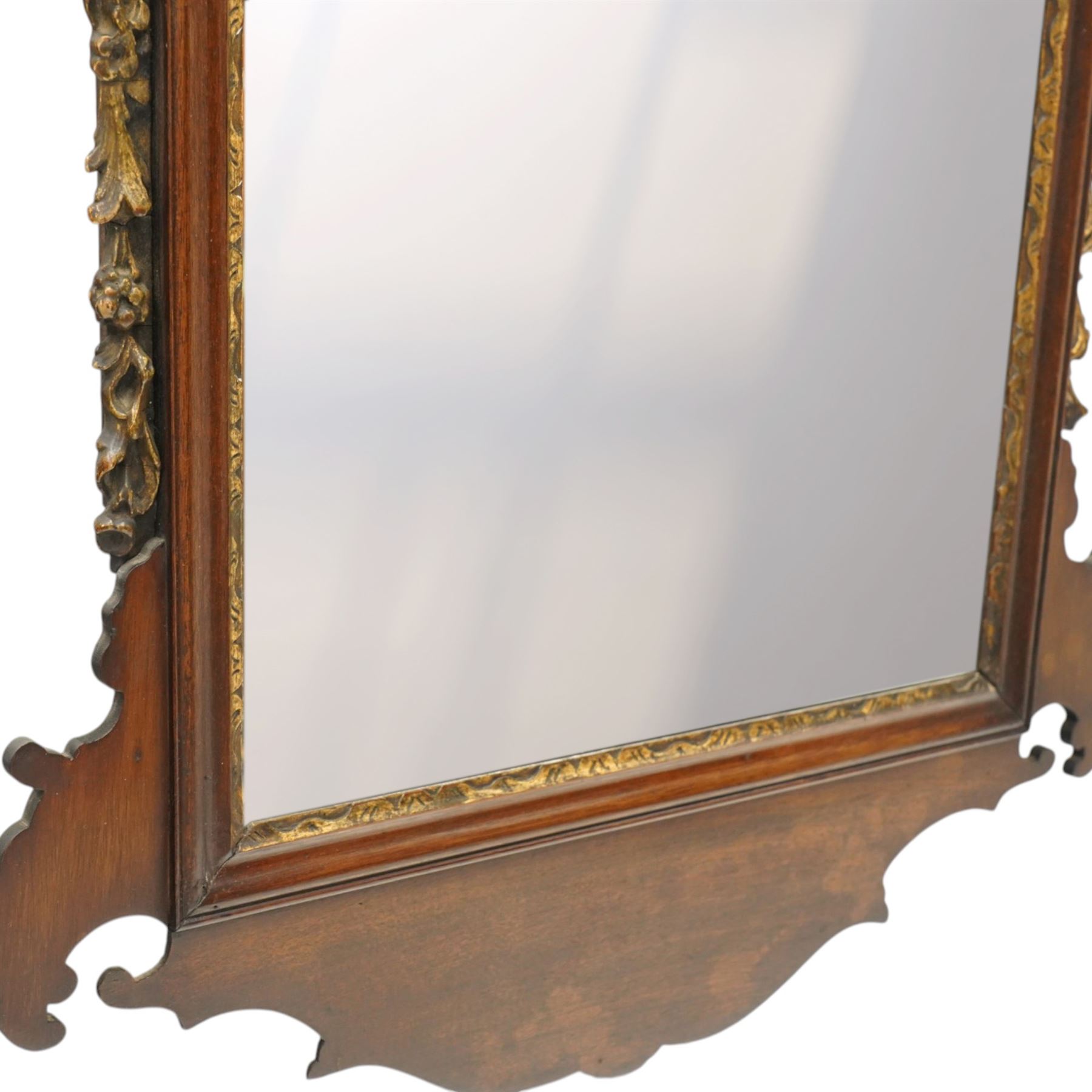 19th century Chippendale design mahogany fret mirror, broken swan neck pediment of foliate design with century bouquet in gilt finish, the rectangular bevelled plate flanked by trailing bellflower motifs, over a shaped terminal