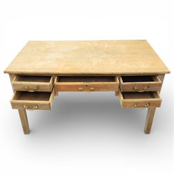 20th century oak kneehole desk, the rectangular top above central drawer and kneehole, flanked by short banks of two drawers, each fitted with brass drop handles, raised upon four plain slightly tapering legs, 75.5cm x 135cm x 73.5cm
