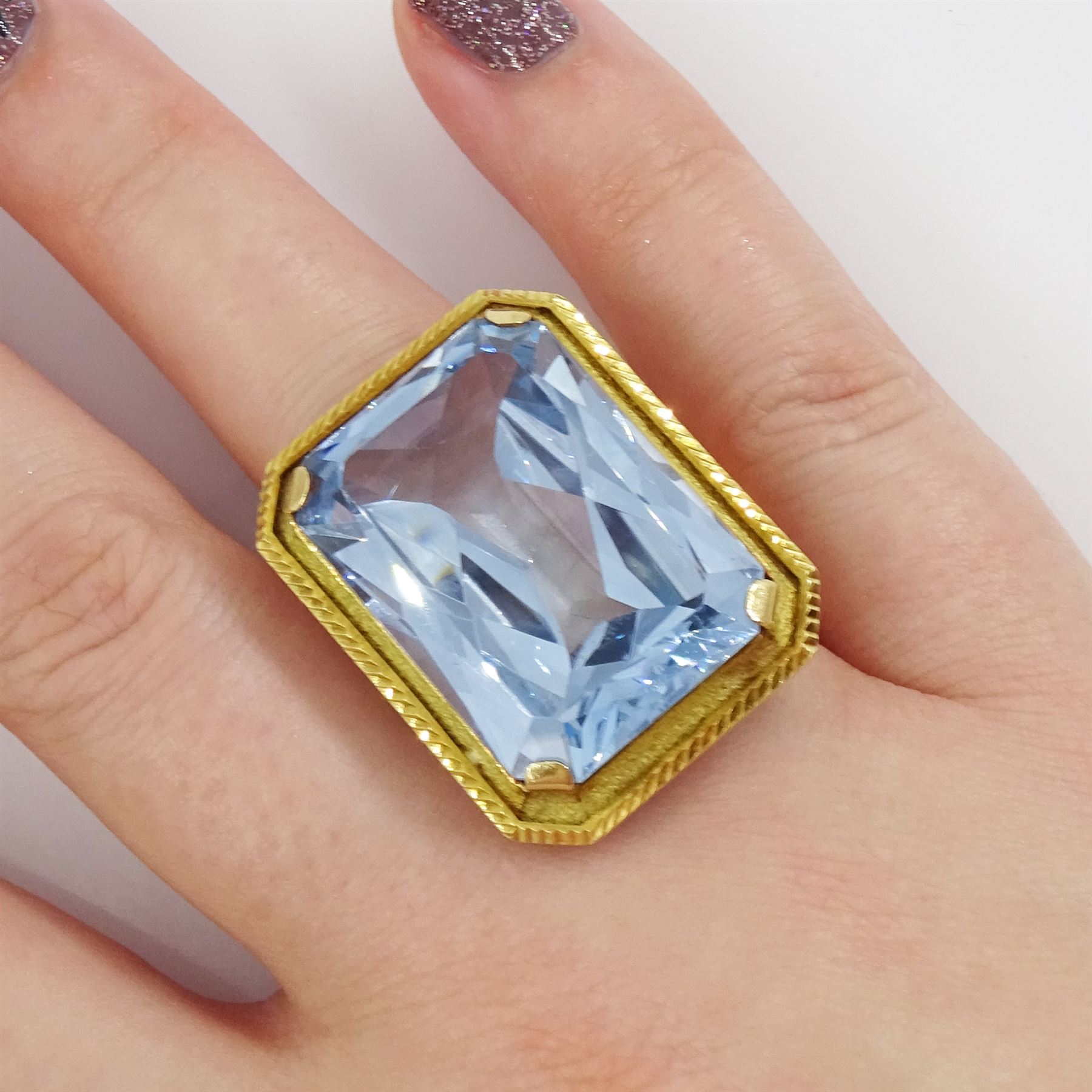 Gold synthetic spinel ring, single octagonal cut synthetic spinel with textured and engraved border