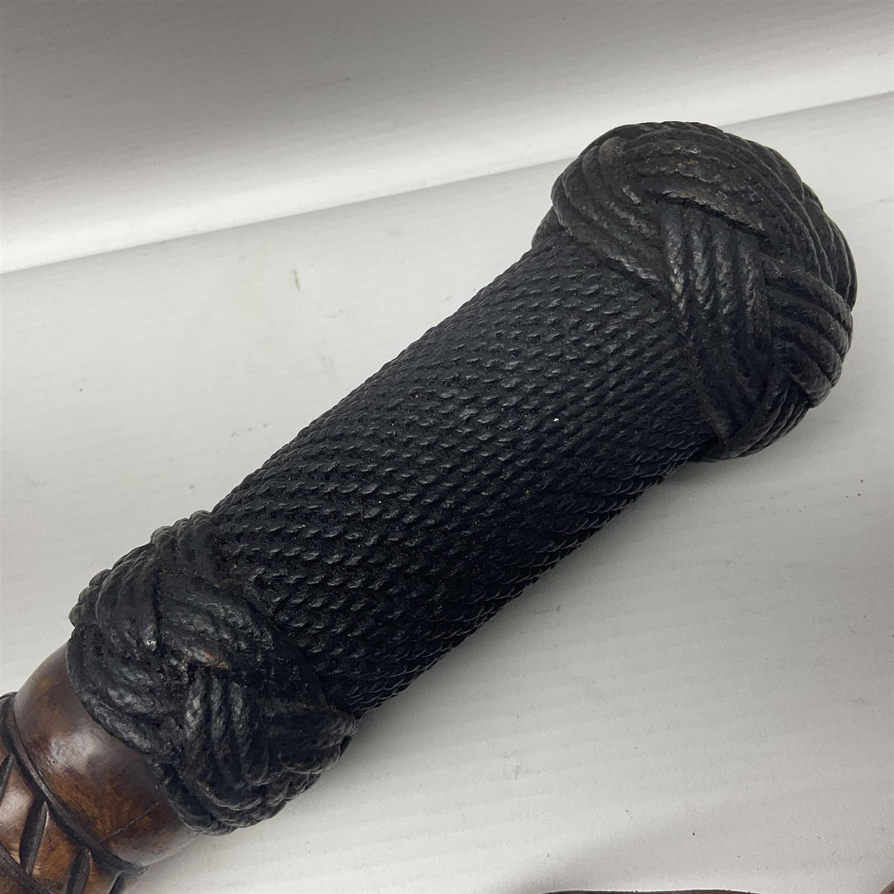19th century wooden walking stick, the handle carved as a snake within a clenched fist, the cane carved with foliate and cross hatched decoration, with a metal spike to base, together with a turned wooden walking stick, with lacquered rope nautical knot handle, tallest L96.5cm