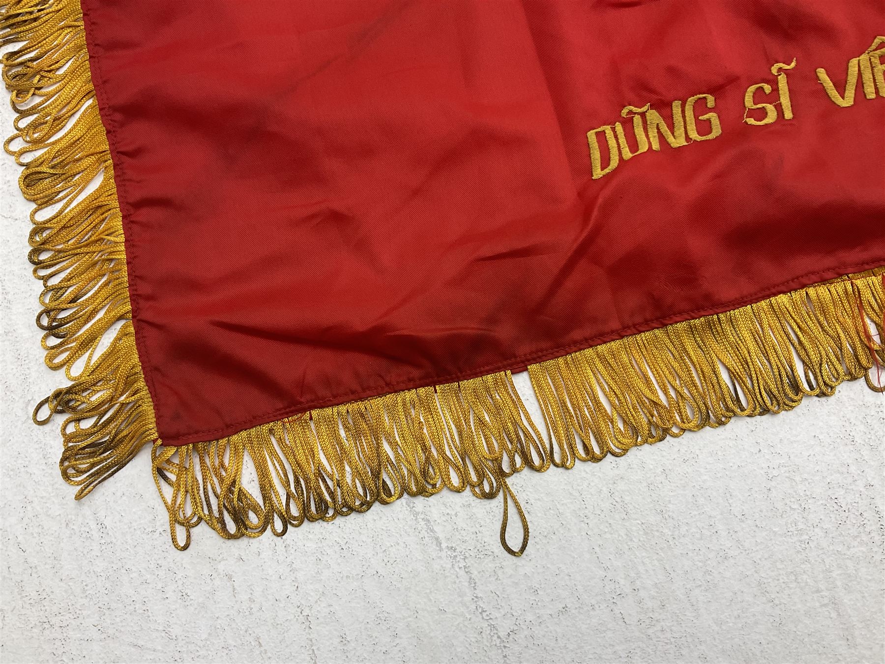 1960s North Vietnam banner embroidered in yellow thread on a red ground, roughly translates as 'Peoples Army of Viet Nam. Warriors of Viet Nam Determined To Keep The Country 1964' around a central military crest with the motto 'Warriors Keep The Country'; tassels to three sides 70 x 100cm