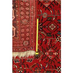 Persian tribal hand-knotted rug, crimson ground, madder field with central stepped lozenge medallion with scattered floral and geometric spandrels with rosette border 
