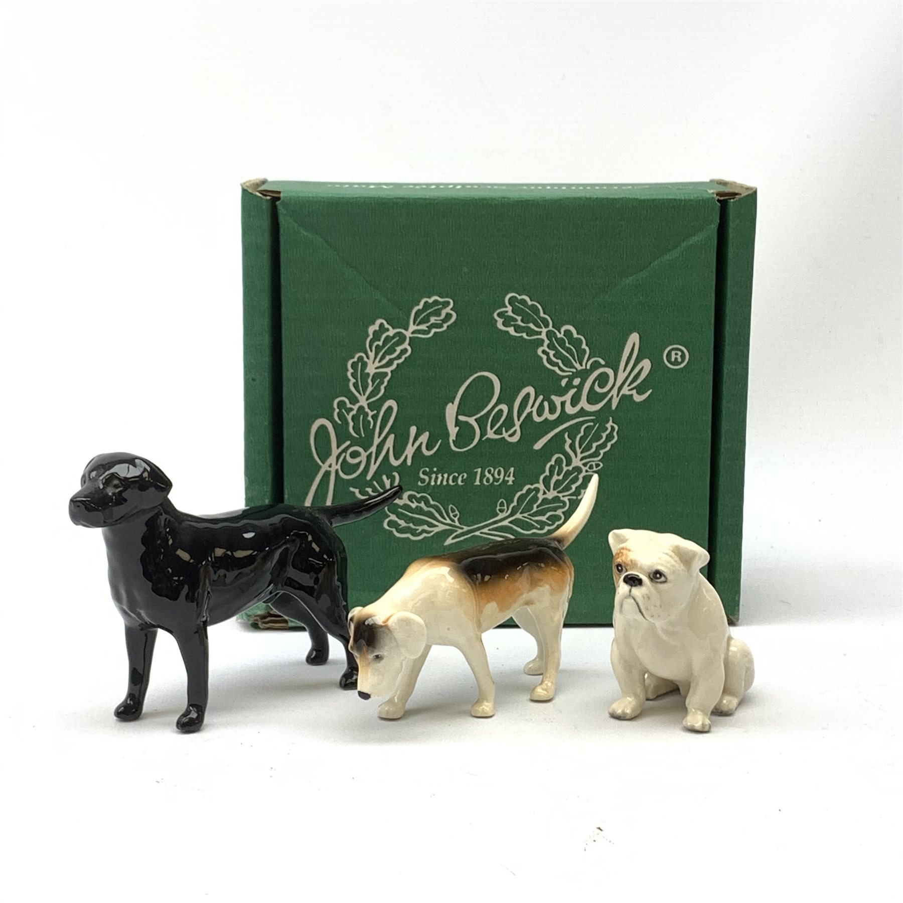 Three Beswick dog figurines, comprising Bulldog, Black Labrador, and Hound, Labrador with maker's box, each with printed mark beneath.
