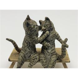 After Bergmann, two cold painted bronze figures, the first modelled as two cats on a bench hugging, the second a cat caning a kitten