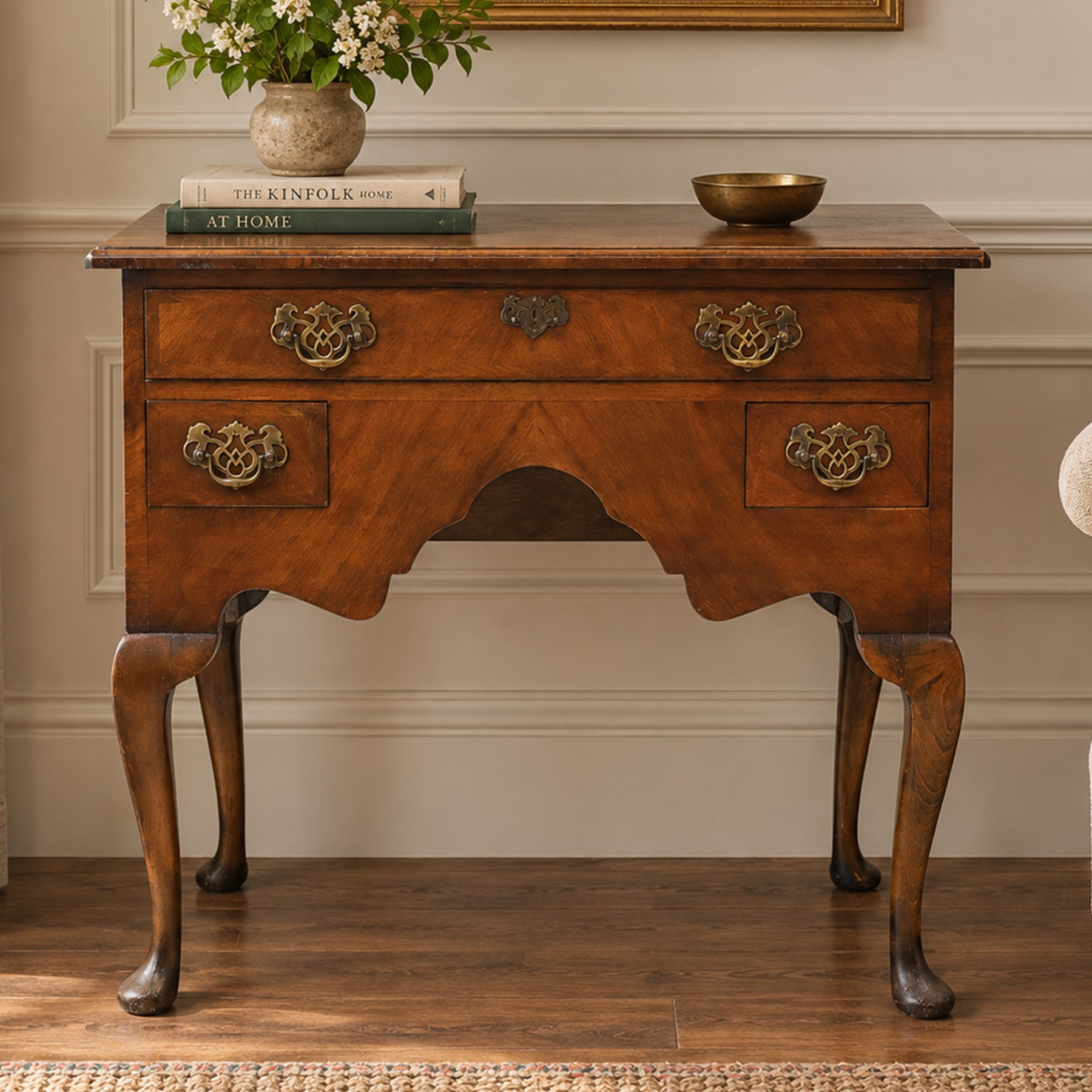 Early 20th century walnut lowboy in Queen Anne style, rectangular crossbanded top over single long drawer and two short drawers with shaped apron, fitted with brass drop handles and backplates, raised on cabriole supports terminating in pad feet
