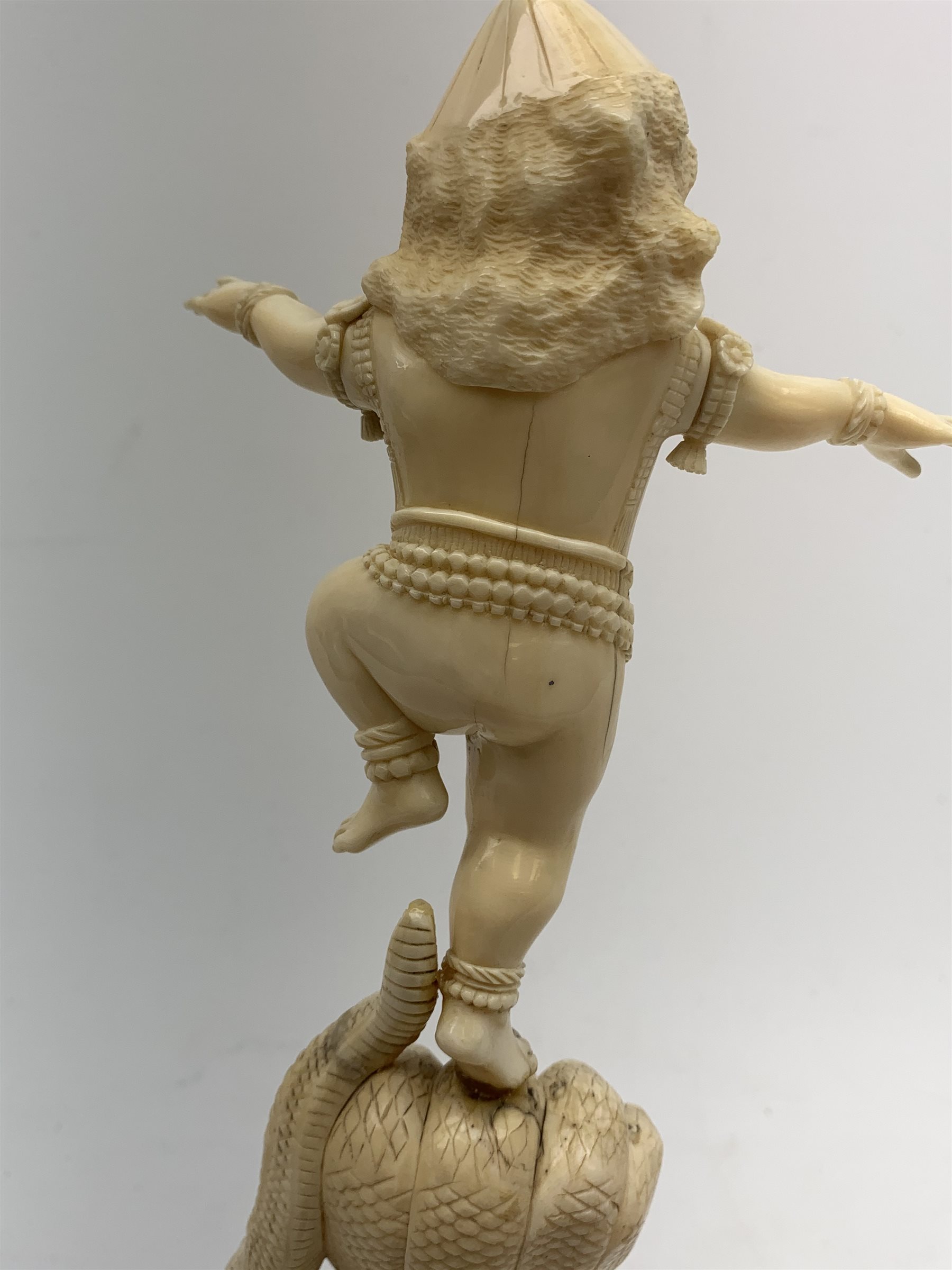A large Japanese carved ivory okimono, modelled as a figure stood upon one leg with arms outstretched, upon a five headed serpent emerging from waves, H30cm.