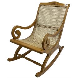 Late 20th century teak framed plantation style rocking chair, cresting rail carved with two elephants with upraised trunks, cane back and seat with scrolled arm terminals, rocker base united by turned stretcher