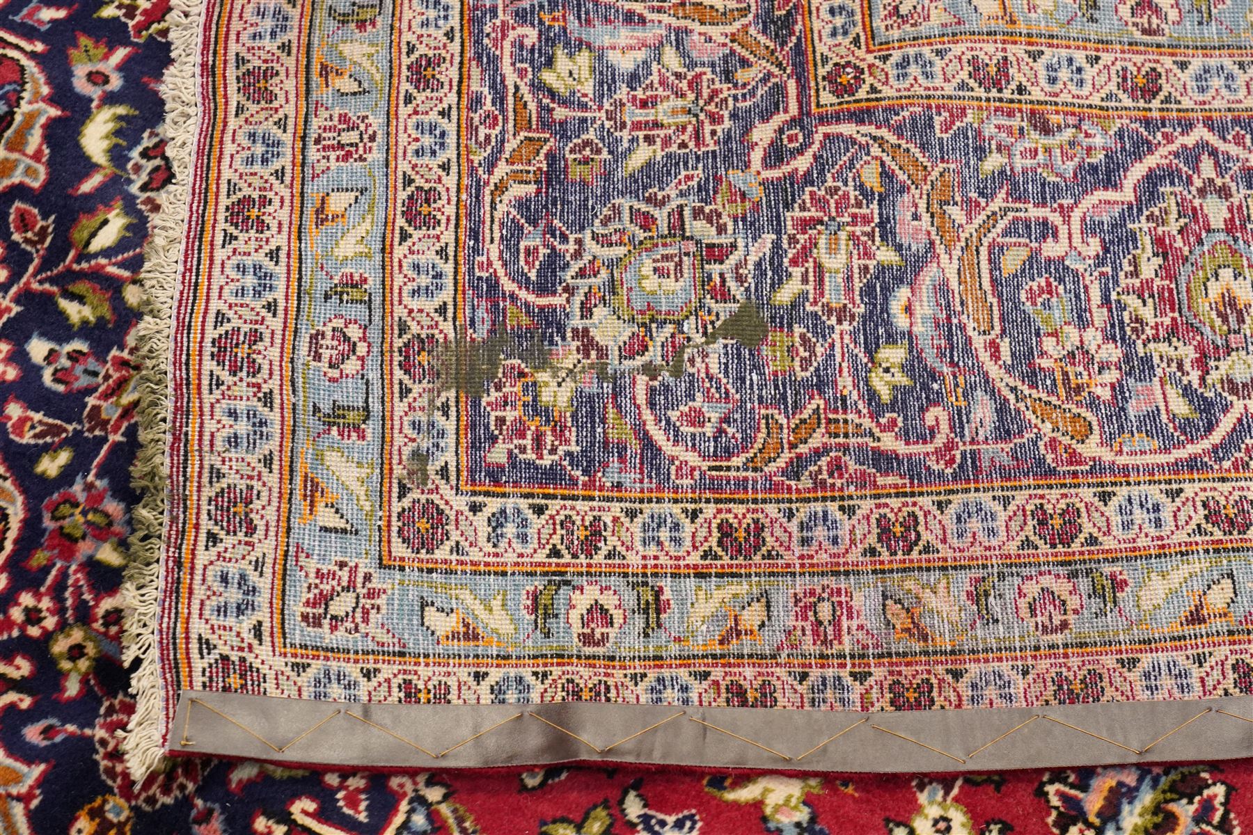 Persian Kashan hand-knotted carpet, madder red ground centred by shaped dark navy and ivory floral medallion with pendants, surrounded by scrolling vines, palmettes and flowerheads, dark navy spandrels, enclosed by dark navy floral border with multiple narrow floral guard stripes