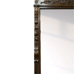Large mid-19th-century Victorian rococo revival carved oak overmantel mirror, the rectangular mirror frame carved in high relief,  arched and scrolled pediment surmounted by a central foliate spray with acanthus scrolls above a finely carved classical mask, frieze decorated with symmetrical  acanthus scrolling, vertical uprights carved with trailing foliage, flowers, and ribbon-tied elements, terminating on a square supports 