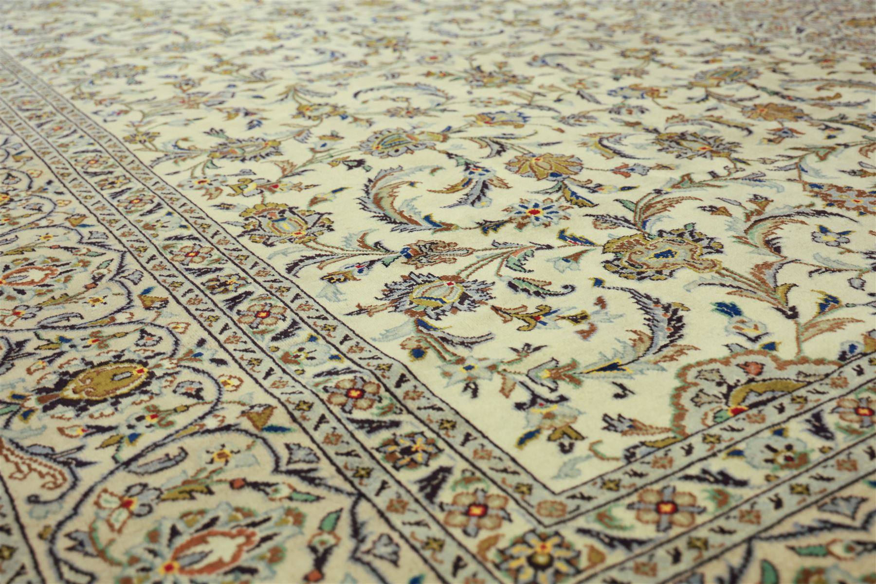 Central Persian Kashan carpet, ivory ground, field with an all-over design of scrolling palmettes and floral sprays in blue and terracotta within a beige ground and pale blue floral border