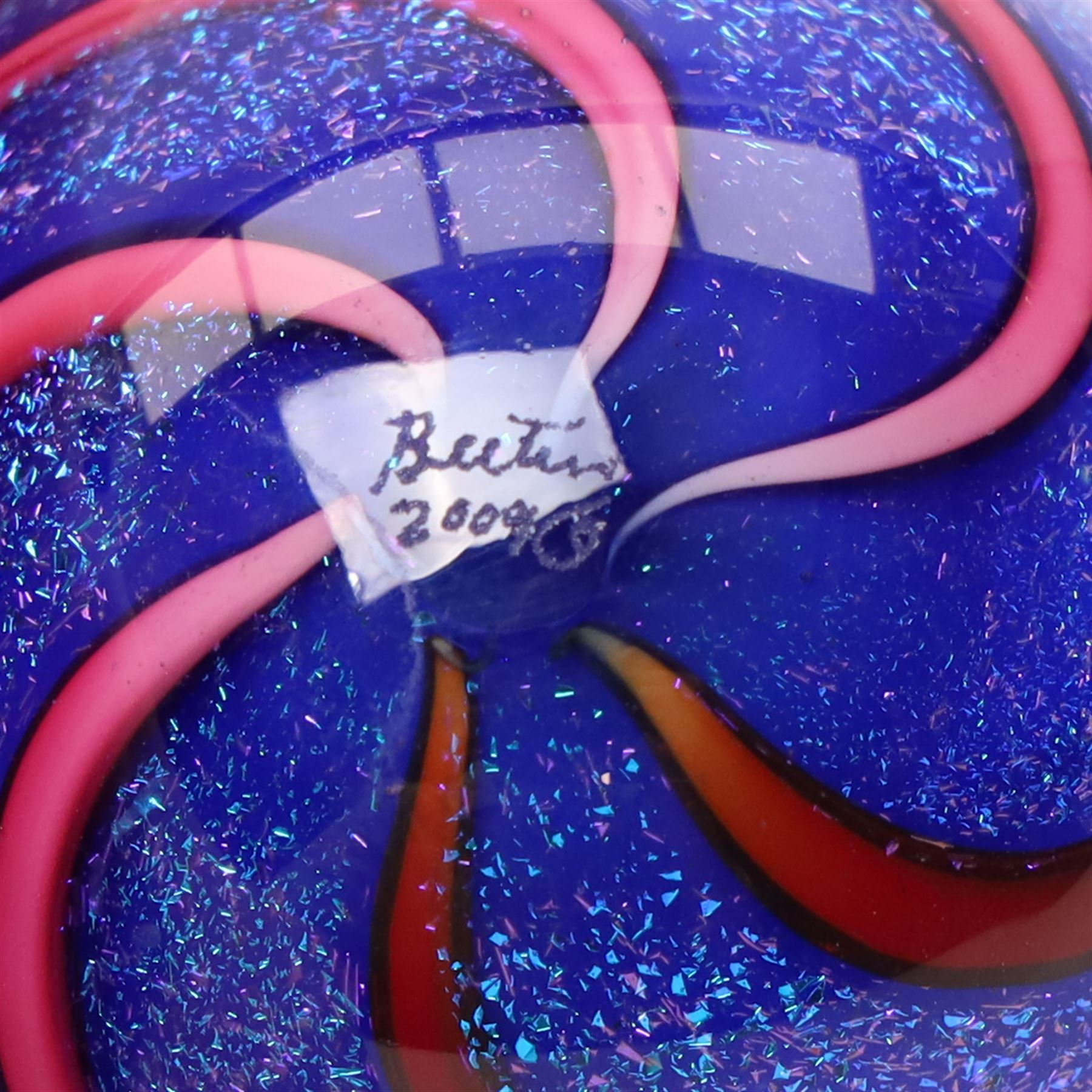 Geoffrey Beetem glass marble, pink and red spiral on a blue ground, signed to base, H5cm 
