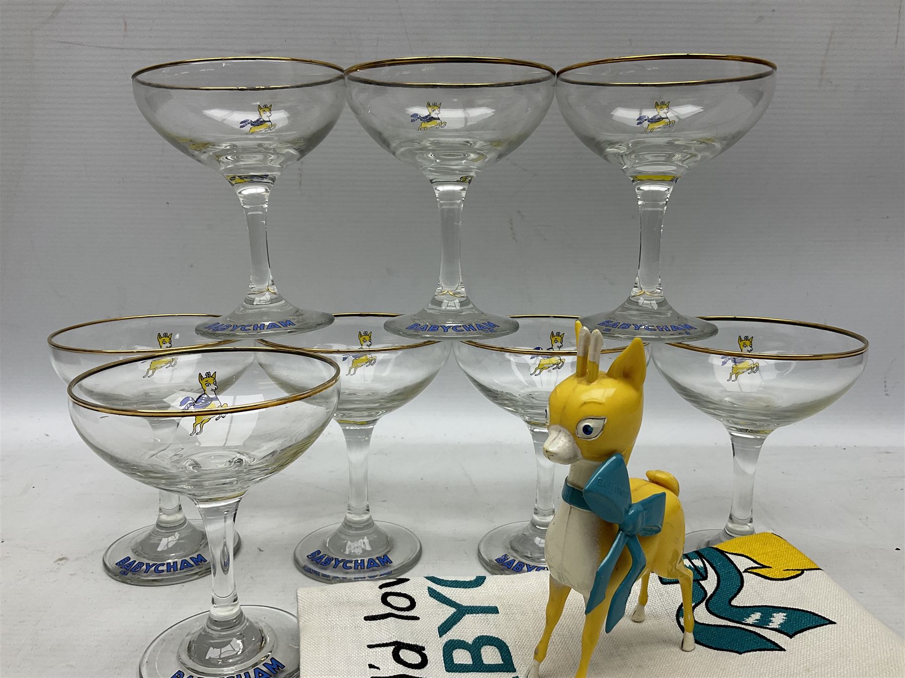 Breweriana; Eight Babycham glasses together with a Babycham plastic fawn mascot and linen I'd Love a Babycham tea towel