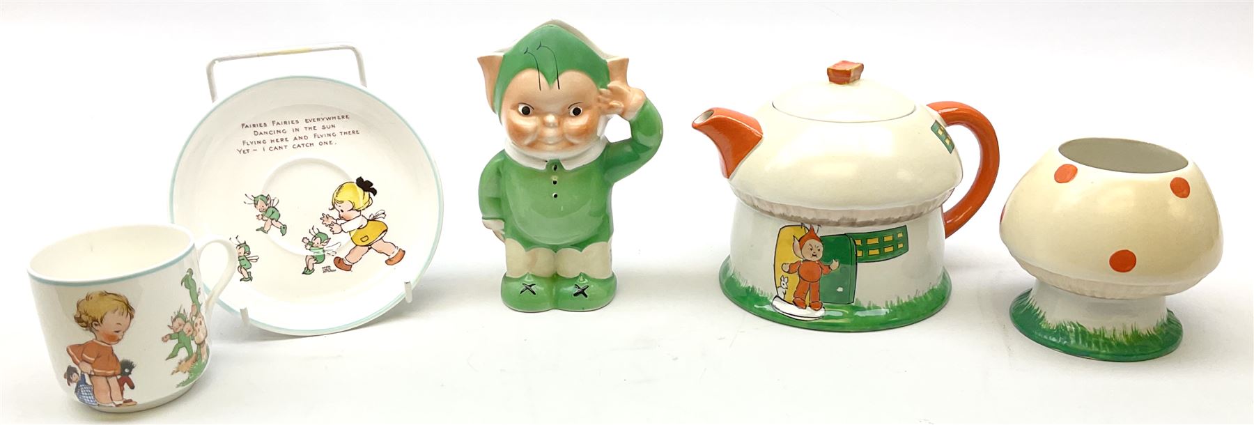 Shelley Boo Boo three piece tea set designed by Mabel Lucie Attwell, comprising teapot modelled as a house, sugar bowl modelled as a toadstool, and creamer modelled as an elf, each with printed marks beneath, together with a Shelley Mabel Lucie Attwell teacup and saucer. 