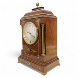 Edwardian- Early 20th century 8-day mahogany mantle clock, with a stepped pediment and brass finial, recessed brass pilasters and brass inlay to the front with a conforming plinth raised on bracket feet, silvered dial with Arabic numerals and steel spade hands within a glazed brass bezel, single train timepiece movement with pendulum and key.

