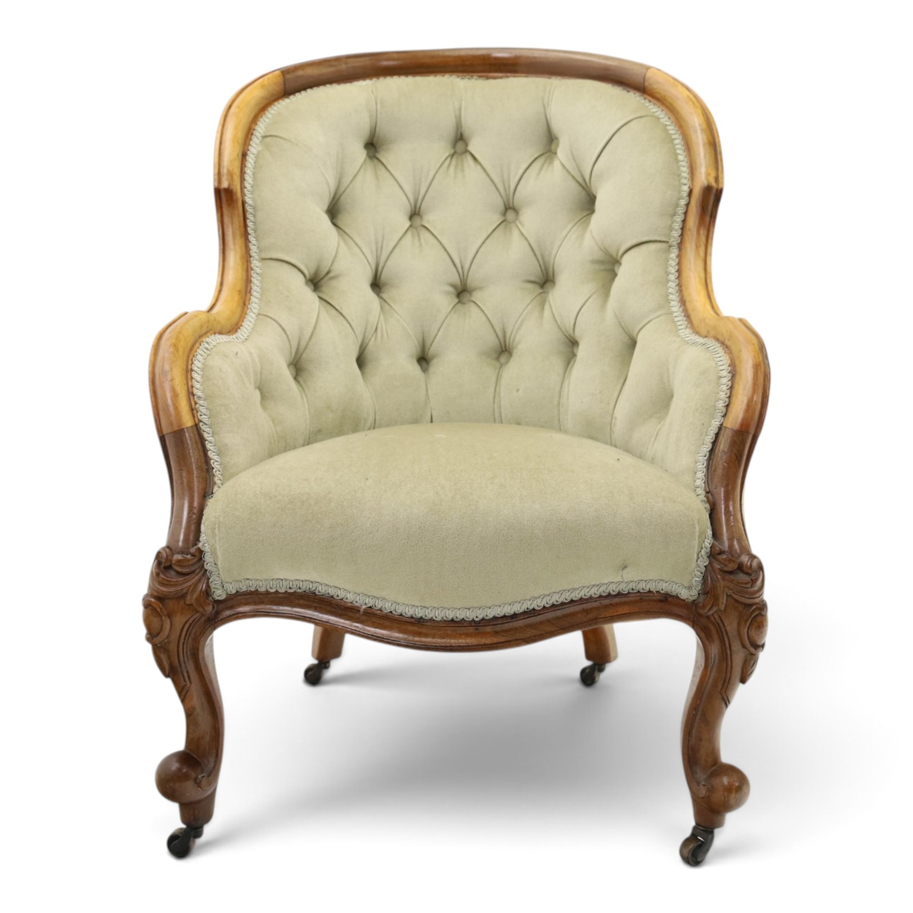 Victorian carved walnut framed armchair with matching stool, the tub-shaped chair with moulded and shaped frame and arm terminals, raised on scrolled cartouche carved supports with scroll feet and castors, buttoned back and sprung seat upholstered in sage green fabric; the small circular footstool with buttoned seat and scroll supports (W36cm H15cm)