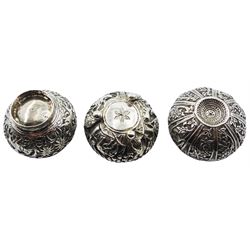 Three Eastern silver open salts, each of circular form and decorated in relief, two examples decorated with animals in a jungle setting, the third with foliate panels, approximate total weight 3.12 ozt (97.2 grams)