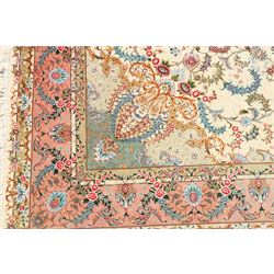 Fine Persian silk inlaid ivory and rose ground Tabriz rug, the busy field decorated with a central foliate pole medallion surrounded by scrolling foliage with trailing flowerheads and bouquets, the multiple guard lines filled with repeating scrolling palmettes and interlocking floral motifs