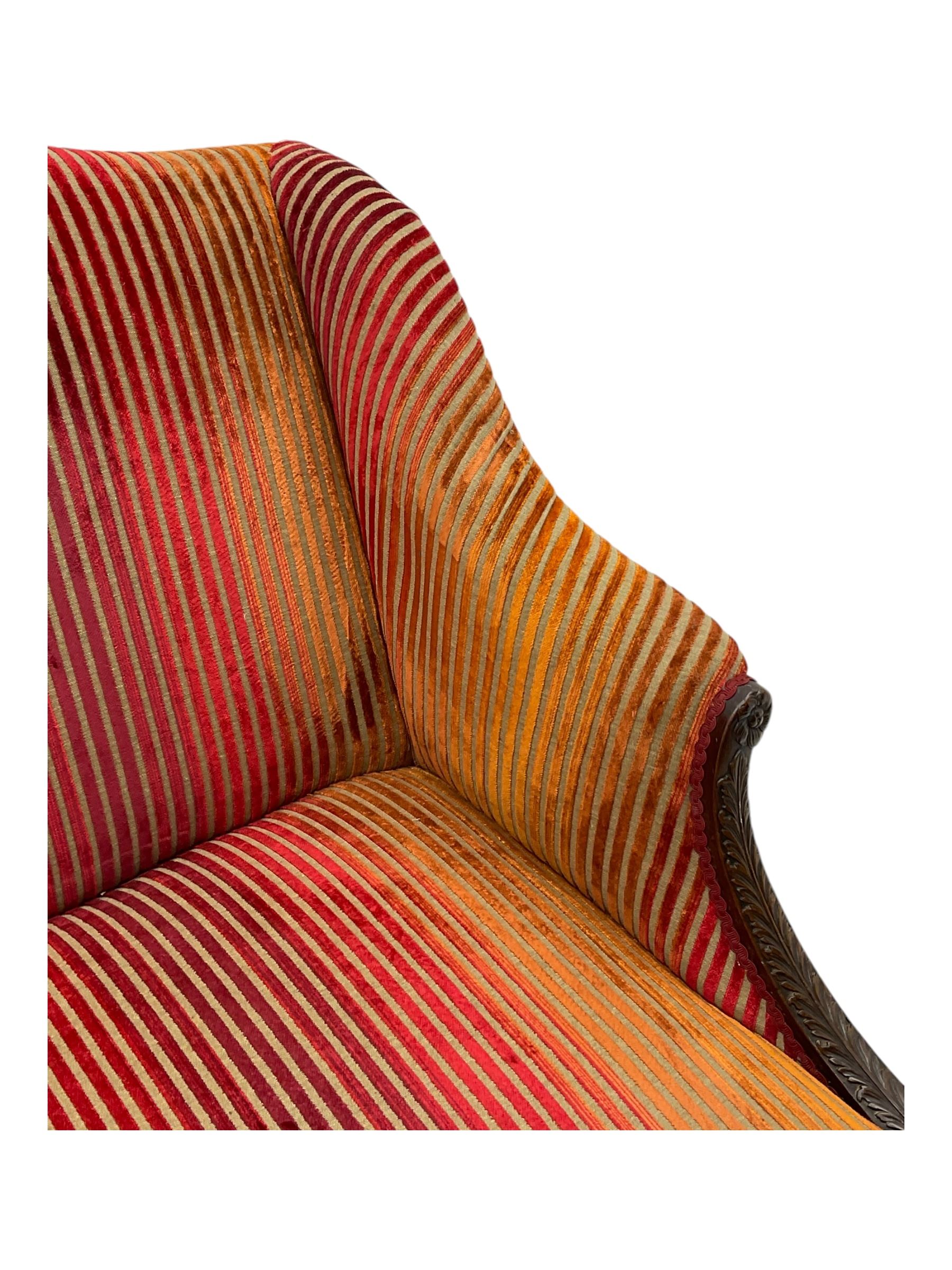 Mid-19th century mahogany two-seat sofa, upholstered in striped velvet fabric, the shaped backrest leading to outward-curved arms, carved apron with scrolling foliate details, raised on cabriole supports terminating in claw and ball feet