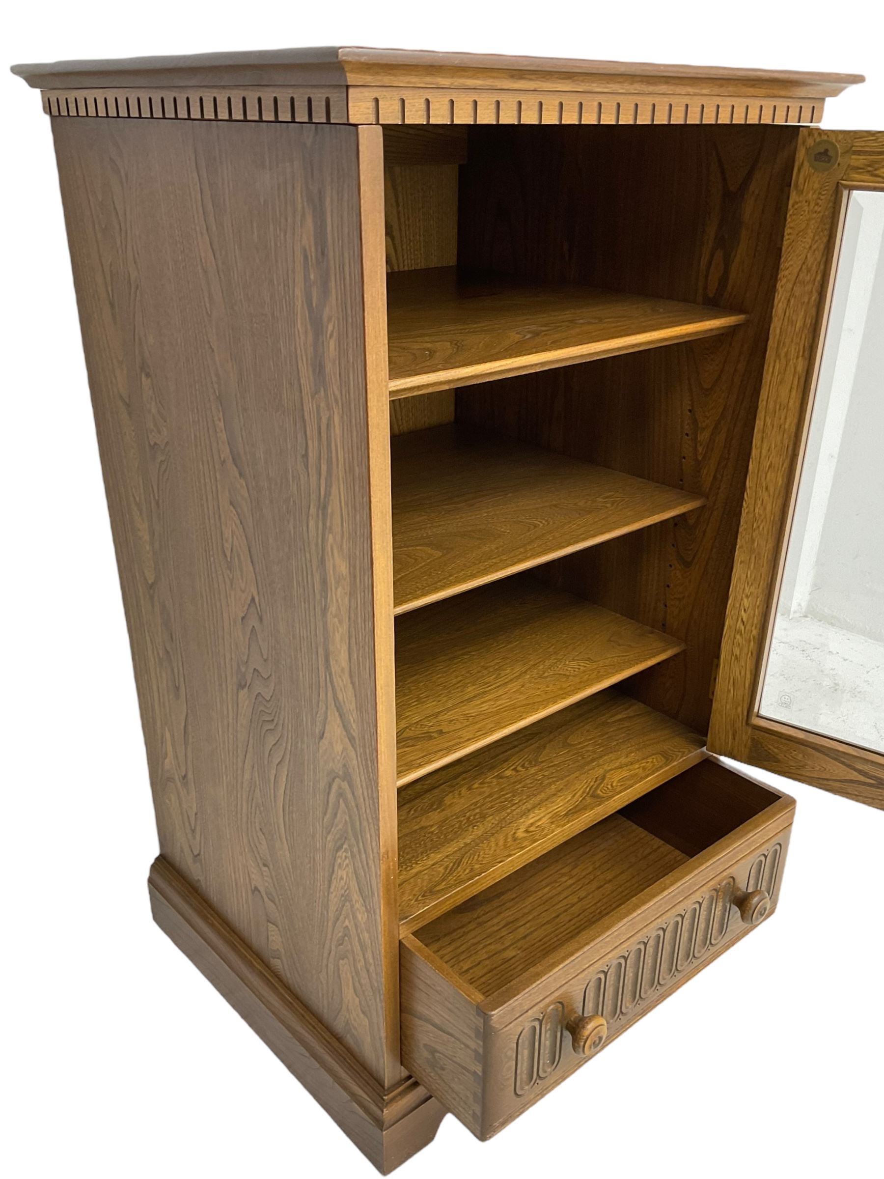 Ercol - mid-20th century dark elm 'Old Colonial' music cabinet, single glazed door enclosing three shelves, single drawer fitted to base