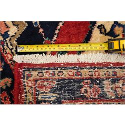 Persian Hamadan runner rug, the vermilion ground decorated with a row of ivory and indigo medallions interspersed with stylised flowering plants, indigo spandrels, enclosed by an indigo floral border and narrow patterned guard stripes