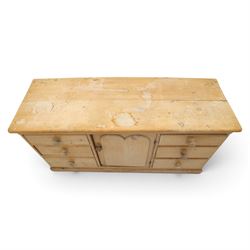 Victorian stripped pine sideboard, rectangular plank top rounded edges, with central cupboard door with shaped panel, flanked by two banks of three graduating drawers with turned knobs, raised on a plinth base 