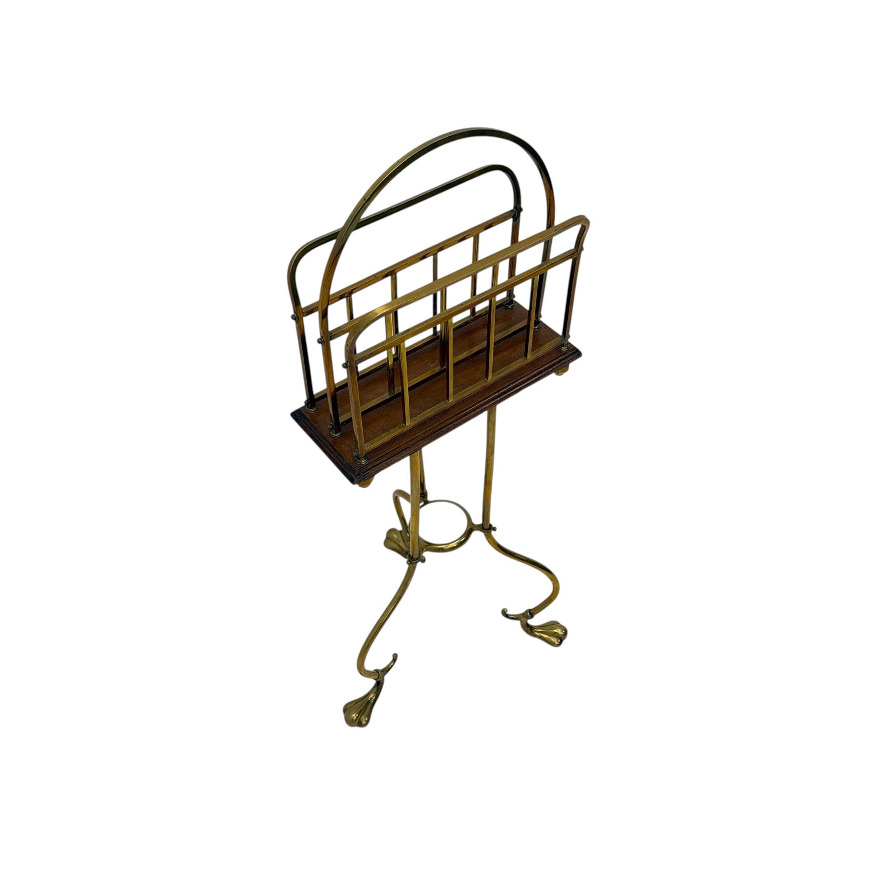 Edwardian oak and brass revolving magazine stand, arched frame with slatted slides and oak base, mounted on a brass column supported by three stylized scrolling legs terminating in pad feet