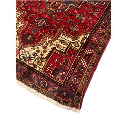Persian Heriz, red ground and decorated with stylised flower and plant motifs, triple band border 