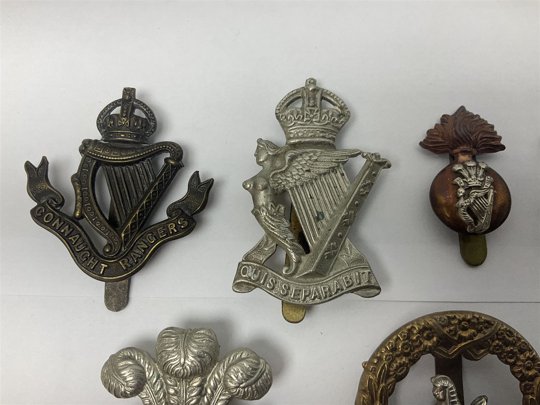 Fourteen cap badges of Irish interest including Royal Dublin Fusiliers inscribed to the slider 'From A. O'Connor 2nd Batt. Dec.2nd 1915', Connaught Rangers, South irish Horse Yeomanry, Inniskilling Fusiliers, Royal Irish Regiment etc; and seven Welsh badges including South Wales Borderers, Welsh Guards, 3rd Bn. Monmouthshire Regt. etc (21)