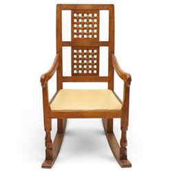 Mouseman - 1940's dark-honey oak rocking chair, high back with pierced double-lattice panel, over a beige-leather upholstered seat, shaped arm terminals above turned octagonal front-supports united by rocker base, with carved mouse signature, by the workshop of Robert Thompson of Kilburn