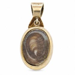 Victorian gold opal and ruby hairwork pendant / locket, the central flower head cluster set with a single oval cut opal surrounded by six oval cut rubies, the reverse with a glazed hairwork panel, engraved decoration throughout and ribbon shaped bale