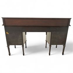 Edwardian Sheraton Revival inlaid plum pudding mahogany serpentine sideboard, rectangular top with raised gallery above bowed frieze drawer finely inlaid with central neoclassical urn motif, flanked by two drawers with swags and ribbon bows, above a cellarette drawer and cupboard, on square tapered supports with spade feet 