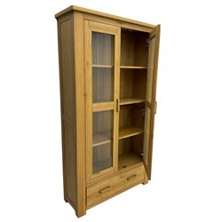 Light oak bookcase display cabinet, fitted with two glazed doors, drawer to base