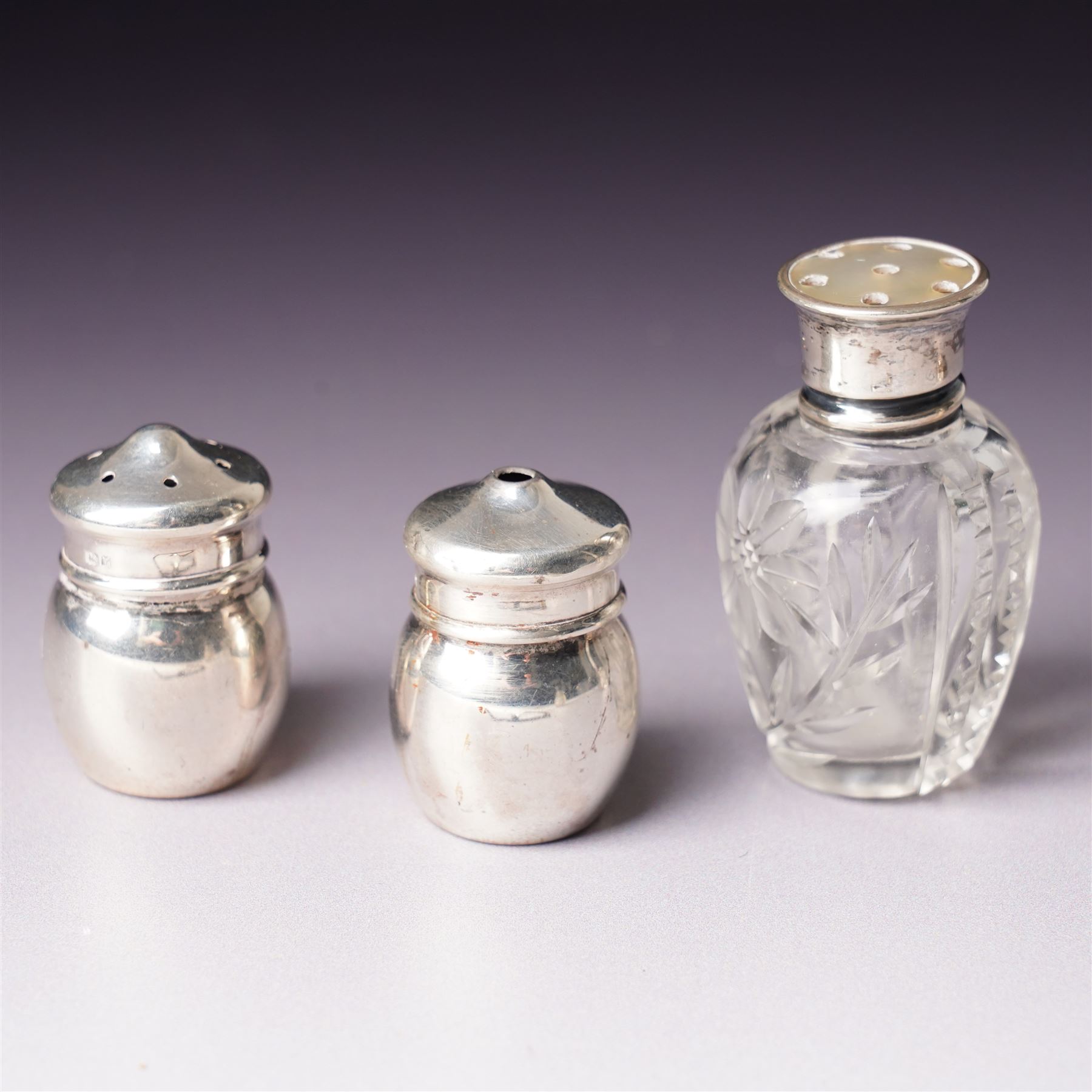 Small glass scent bottle with silver and red enamel cover, Edwardian silver cased scent flask with engraved decoration, heptagonal silver napkin ring, pair of small silver barrel shape salts, glass pepperette with silver and mother of pearl cover, small silver stone set fork by William Robb and a silver salt spoon