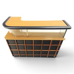 Barget of London - Mid 20th century L-shaped teak and black vinyl cocktail bar, shaped top with gilt metal banding and black cushioned edge over glazed upper section and open serving shelf, the reverse fitted with shelves, the front with applied lattice mouldings over black vinyl, on plinth base