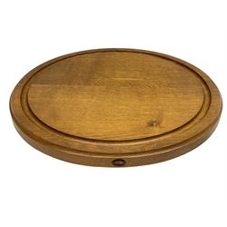 Acornman - oak chopping board, circular form with moulded edge and sunken groove, the side carved with acorn signature and recessed handles, by Alan Grainger, Brandsby