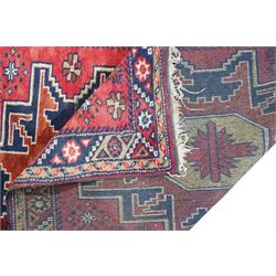 Caucasian pale red ground rug, the field decorated with three large medallions and stylised flower heads, within repeating border 