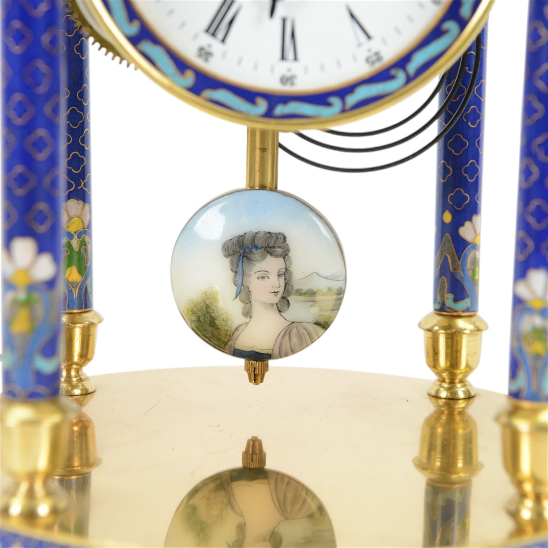 20th century- 8-day cloisonne styled rotunda clock, with six decorative enamel pillars and floral decoration to the base and top, visible pendulum with a portrait depiction of a young lady, four inch enamel dial with Roman numerals, minute markers and trefoil steel hands, twin train spring driven rack striking movement sounding the hours and half hours on a coiled gong.   