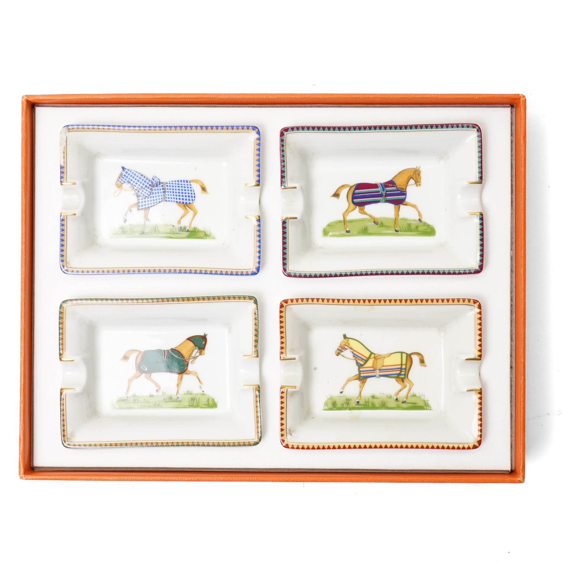 Hermès - set of four miniature porcelain ashtrays, each decorated with a horse in differing blanket, with gilt and coloured borders, in contrasting colour with various horse-coats, in original fitted box